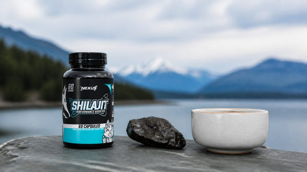 Nexus Shilajit capsule bottle beside a rough rock sample and a cup of tea on a slate board
