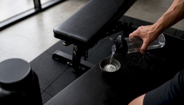 Hand preparing creatine powder and shaker bottle