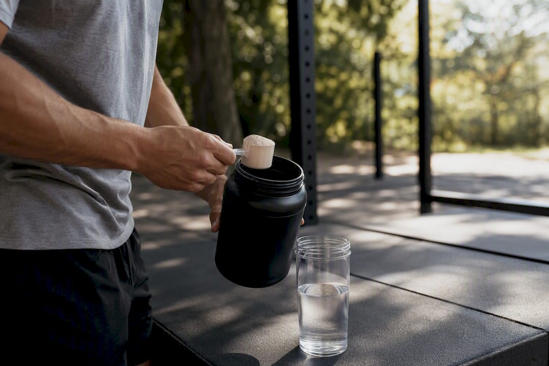 Hands scooping powder supplement into shaker