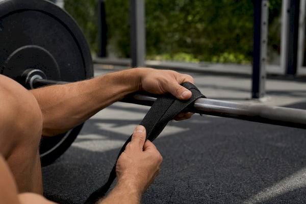 Hands wrapping lifting straps on barbell