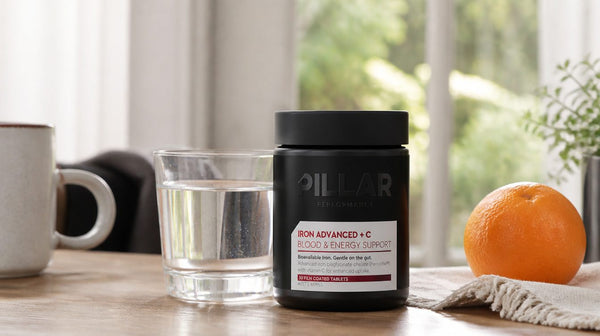 Pillar Iron Advanced + C bottle with a glass of water and an orange on a breakfast table, coffee cup pushed aside
