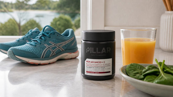 Pillar Iron Advanced + C bottle on a kitchen bench next to running shoes, fresh spinach and a glass of orange juice
