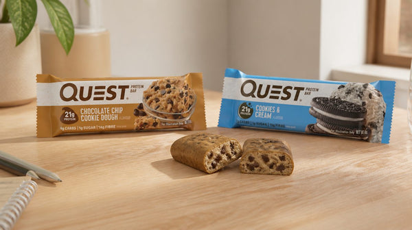 Quest protein bars in Choc Chip Cookie Dough and Cookies N Cream spread on a desk, one unwrapped and cut in half