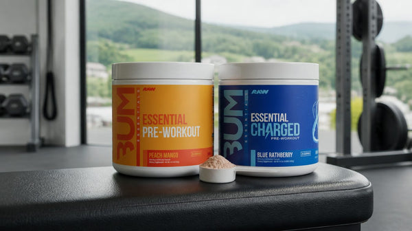 CBUM Essential Peach Mango and CBUM Essentials Charged Blue Rathberry tubs side by side on a gym bench