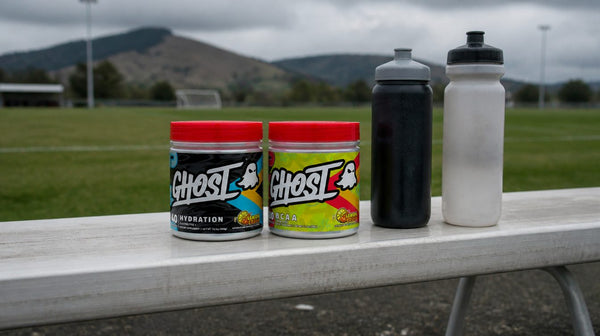 Ghost Hydration and Ghost BCAA tubs on a sideline bench with two drink bottles