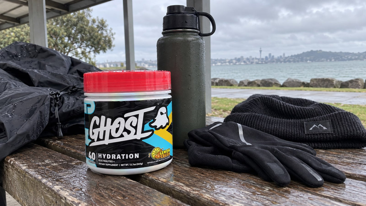 GHOST Hydration Lemon Crush beside a bottle, gloves and beanie on a sheltered bench.