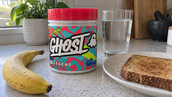 GHOST Legend Blue Raspberry pre-workout beside toast, a banana and water.