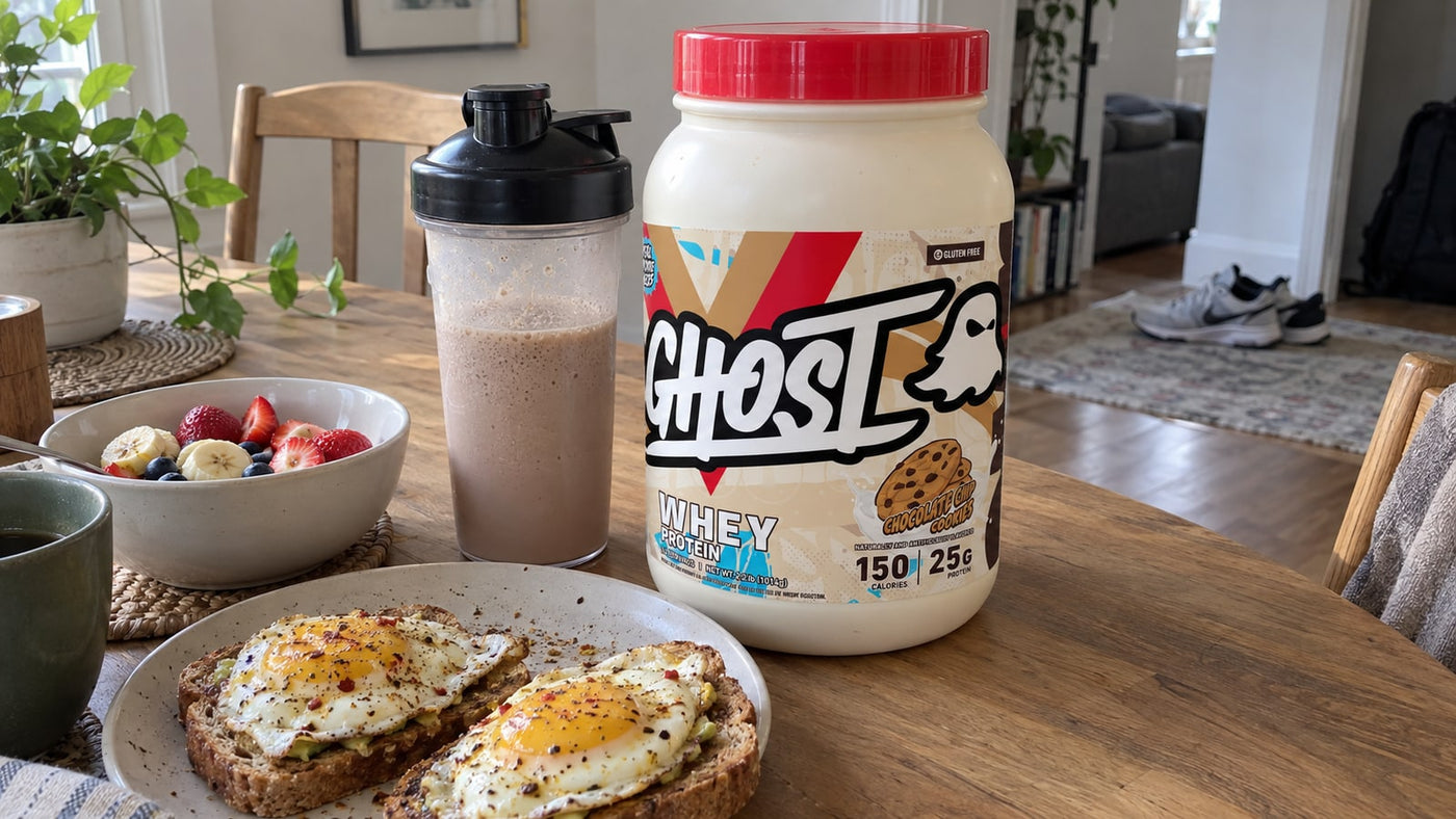 GHOST Whey Chocolate Chip Cookies beside a shake, eggs on toast and fruit at home.