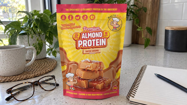 Macro Mike Almond Protein Salted Caramel beside reading glasses and a notebook.