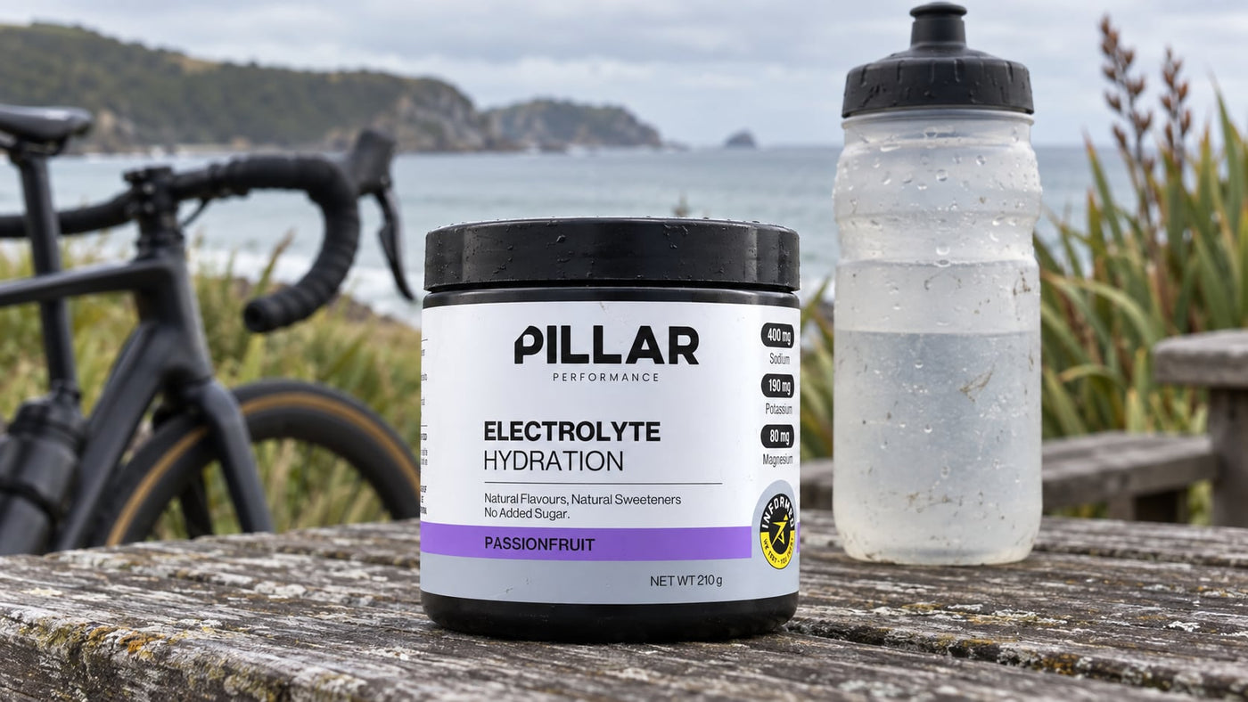 Pillar Performance Passionfruit Electrolyte Hydration tub and cycling bottle at a coastal stop.