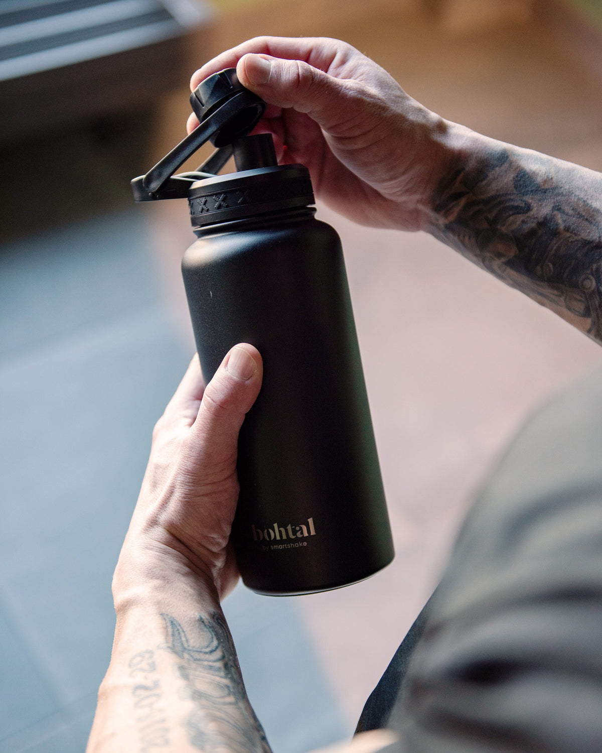 SmartShake Bohtal Insulated Sports Bottle Black held in hand with lid opening